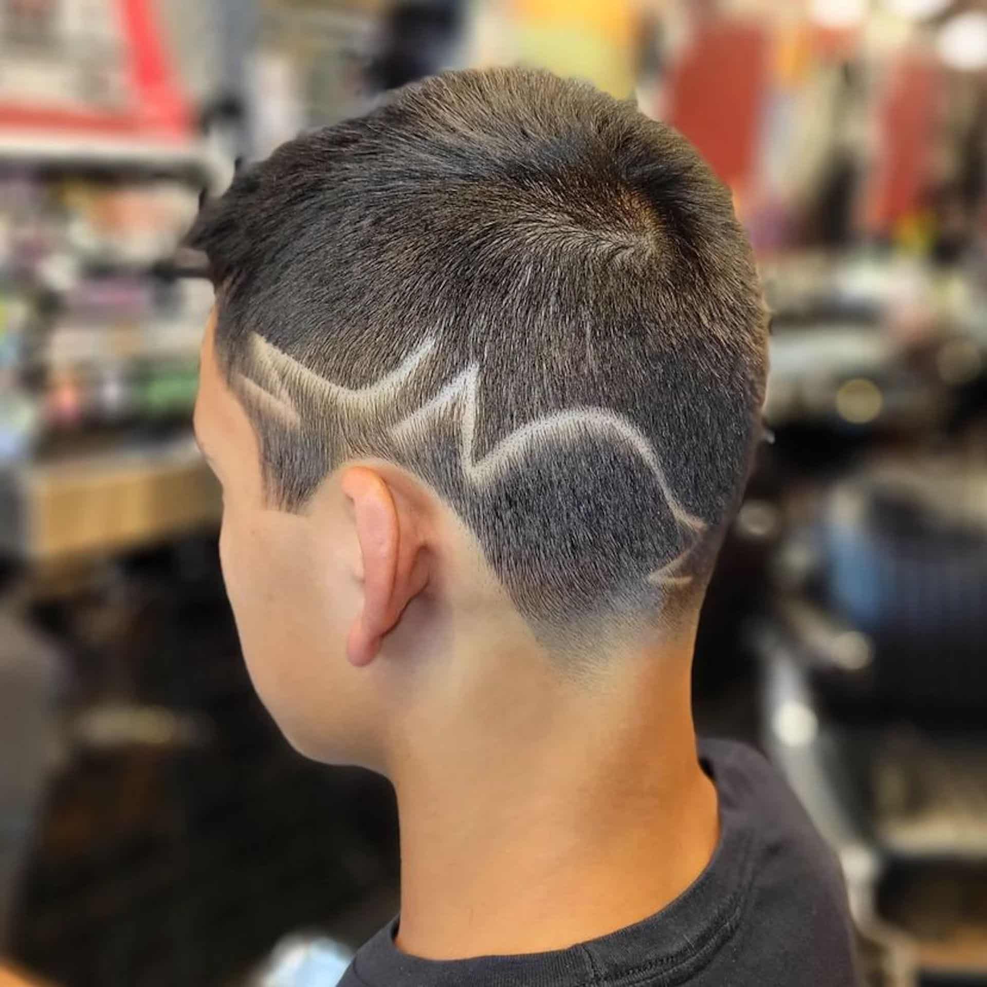 A young boy with an undercut with custom design by Floyds in the side of his head.