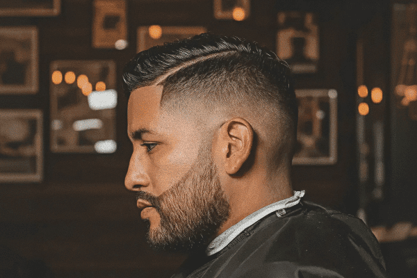 A young hispanic male with a precision fade and beard trim from Floyd's Barbershop.